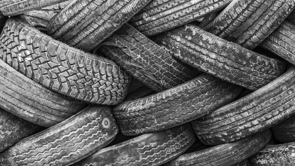 Large pile of used tires tangled together in grayscale image.
